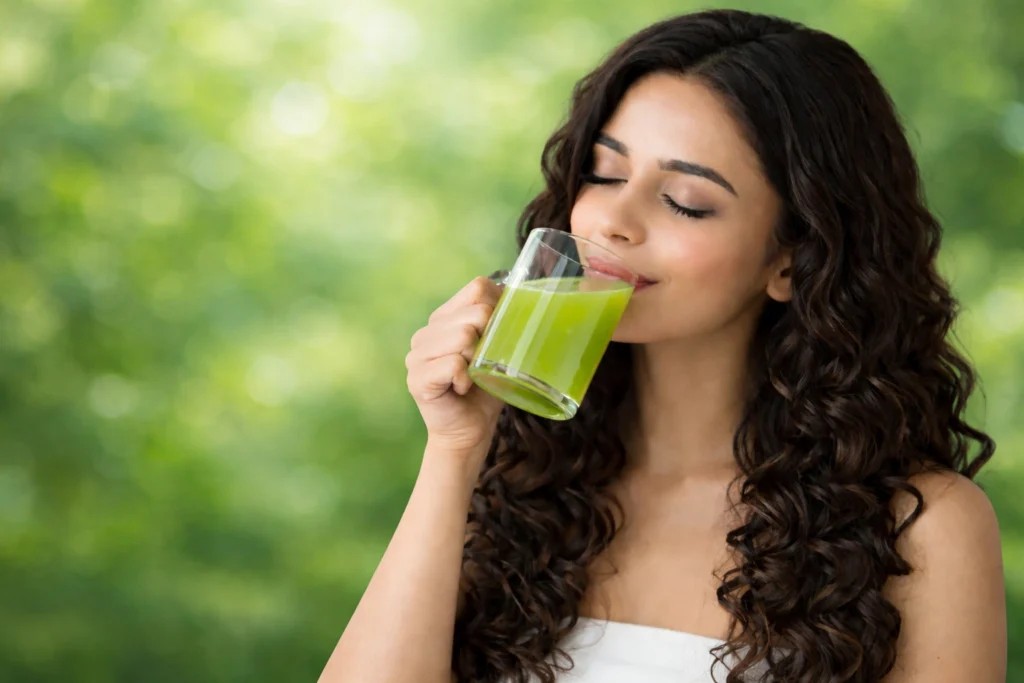 Woman drinking amla juice with long curly hair to enjoy amla juice benefits and natural glow.